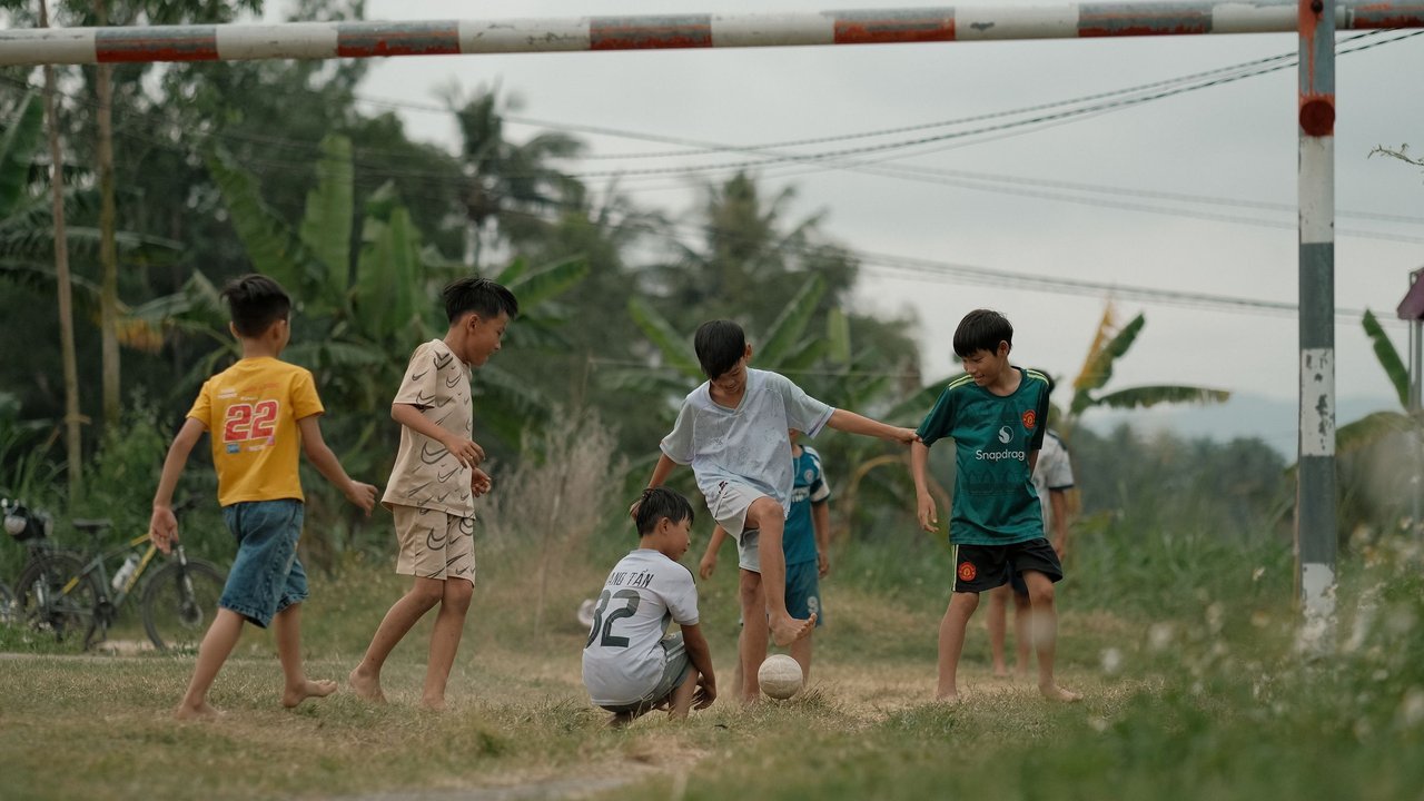 Meninos jogam futebol num campo de grama ao ar livre