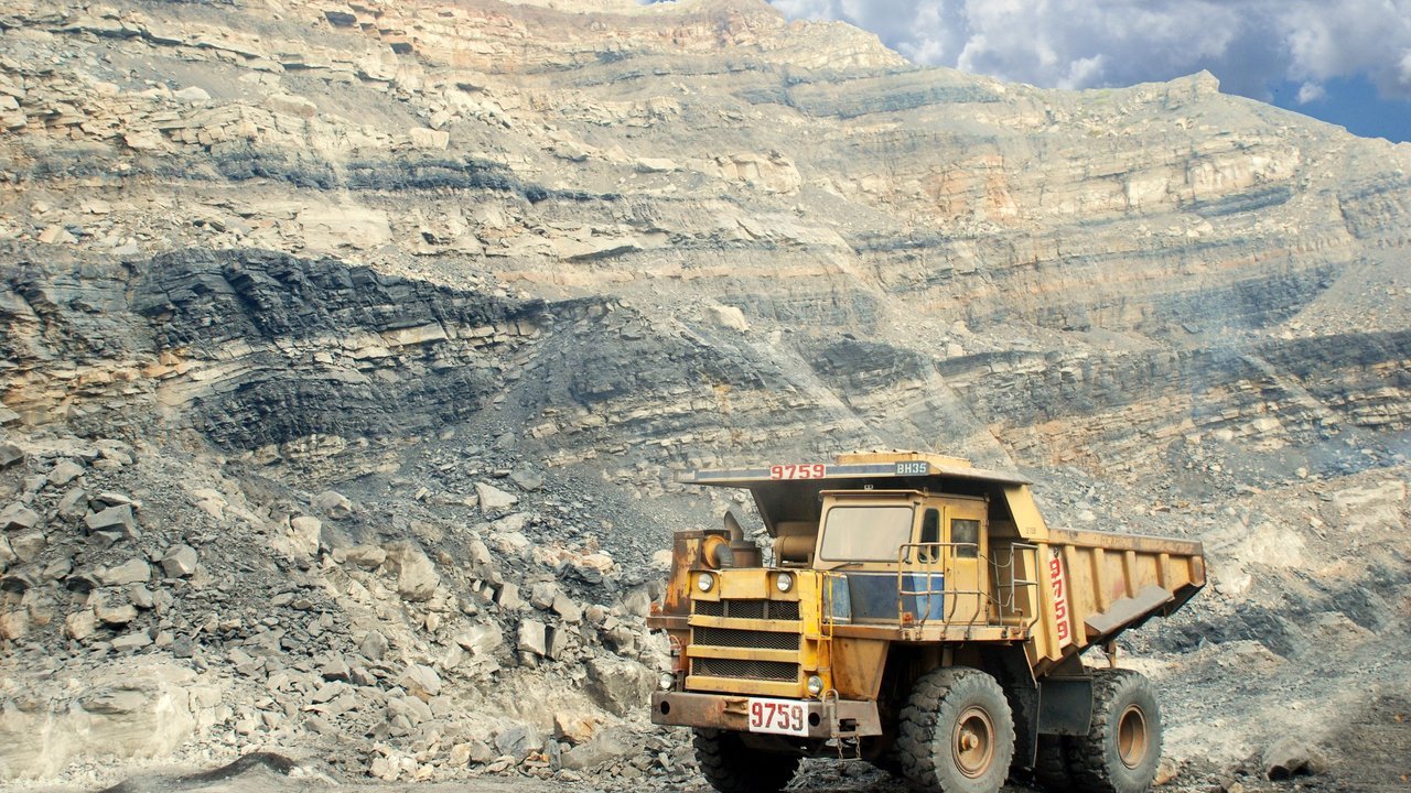 Caminhão de mineração amarelo numa pedreira, entre paredões de rocha