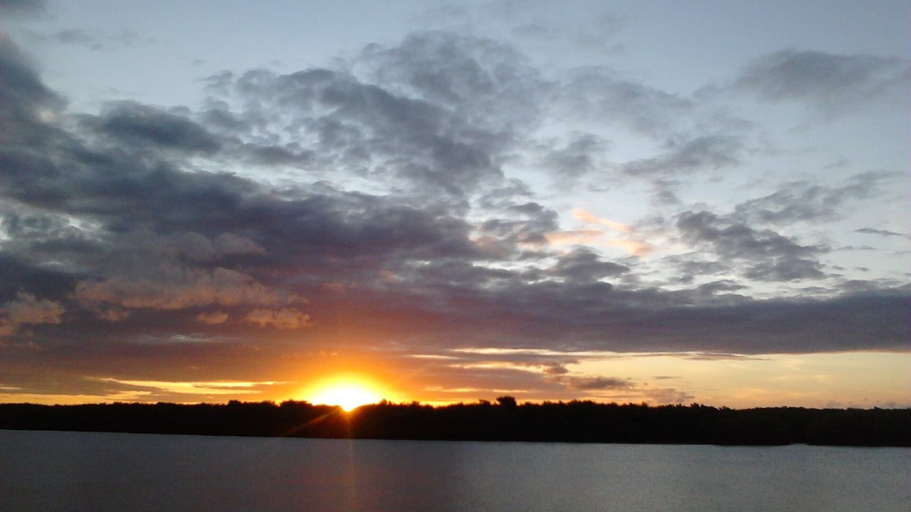Pôr do sol sobre o rio em Aracaju, Sergipe, com barcos de pescadores na água