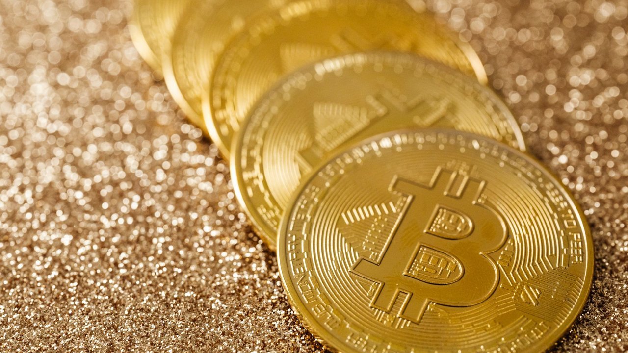 Moedas douradas com o símbolo do bitcoin sobre fundo brilhante